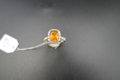 an orange sapphire and diamond ring on a black surface