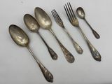six silver spoons and a fork on a white surface