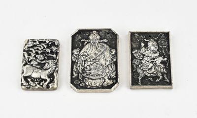 trois objets métalliques argentés posés sur une surface blanche, sur fond blanc