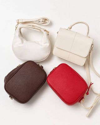 trois sacs à main de couleurs différentes posés sur une surface blanche, avec un cordon