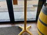 une table jaune au plateau noir, à côté d'un tonneau en bois