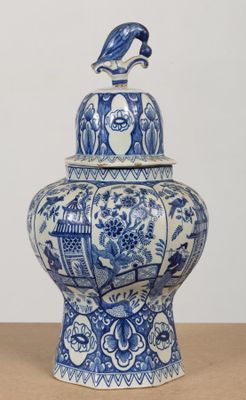 un vase bleu et blanc surmonté d'un oiseau