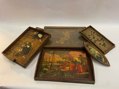 trois plateaux en bois décorés de peintures, posés sur une surface blanche