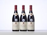 three bottles of red wine sitting on top of a table