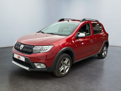 La Dacia rouge est garée dans une pièce au sol noir.