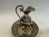 a silver plate with a silver pitcher on top of it