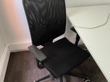 a black office chair sitting next to a white desk