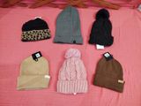 several hats are laid out on a pink blanket on a bed