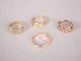 four gold rings on a white surface with a diamond in the middle