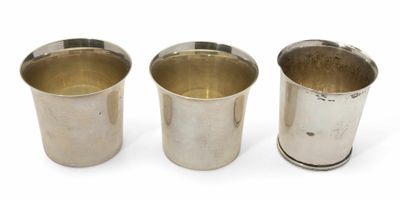 trois tasses en argent posées l'une à côté de l'autre sur une surface blanche