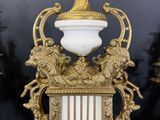 a gold and white clock on a table next to other gold and white objects