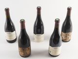 six bottles of wine are lined up in a row on a white surface