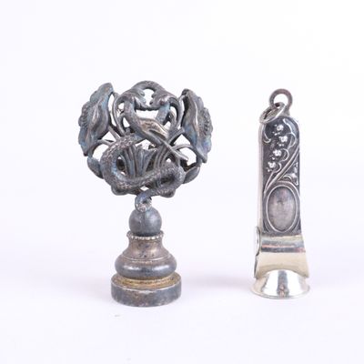 un petit objet en argent à côté d'un autre objet en argent, plus petit