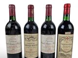 three bottles of red wine sit next to each other on a white surface