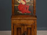 an old wooden cabinet with a painting of a woman sitting on top of it