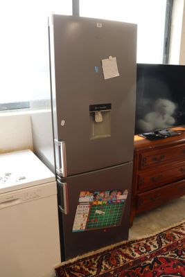 a refrigerator in the corner of a room with a tv on