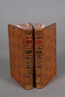 two old books are sitting on top of each other on a table