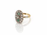 a close up of a ring with a diamond and emerald