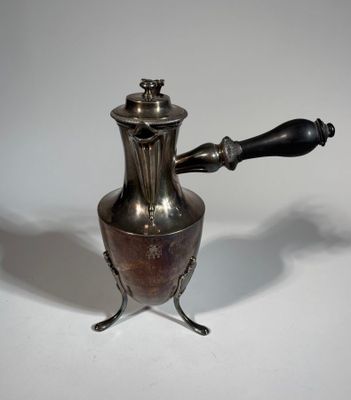 a silver coffee pot with a black handle on a white table