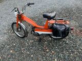 une trottinette orange avec un sac noir à l'arrière