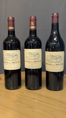 trois bouteilles de vin sont alignées sur une table en bois