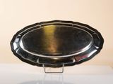 a silver plate on a stand on a white surface