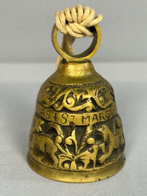 une vieille cloche en laiton entourée d'une corde, posée sur une surface blanche