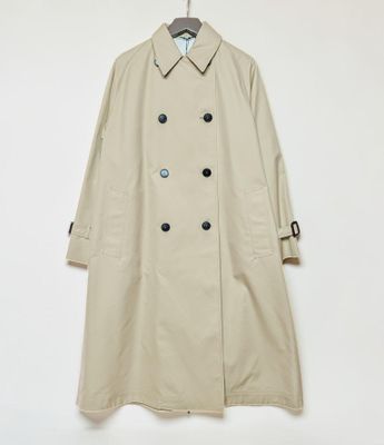 a beige trench coat hanging on a white wall