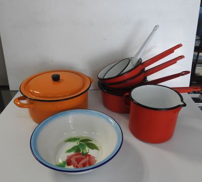 Plusieurs casseroles et poêles sont posées sur une table, à côté d'un saladier et d'une cuillère.