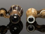 two pairs of binoculars sitting on top of each other on a reflective surface