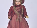 une poupée qui porte une robe rouge et un chapeau