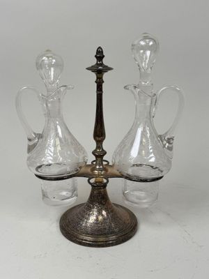 three glass decanters on a metal stand with a white background