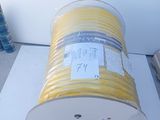 a roll of yellow wire on the ground next to a wall