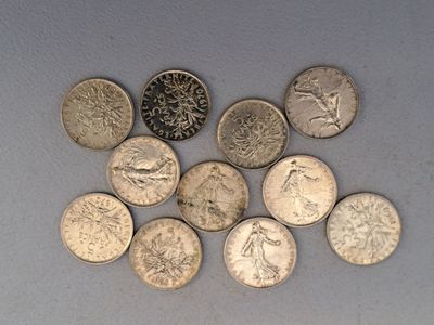 plusieurs types de pièces de monnaie sont disposés sur une surface blanche