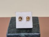 a pair of gold stud earrings sitting on top of a marble block