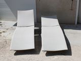 deux chaises longues posées sur le béton devant un immeuble