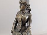 statue of a woman sitting on a stool with a hat on her head
