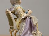 a figurine of a woman sitting on a chair