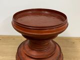 wooden pedestal on a table with a white wall in the background