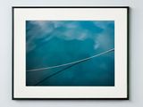 a framed photograph of a bird sitting on a wire against a blue sky