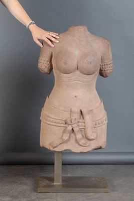 une femme debout à côté d'une statue représentant une femme les mains posées sur la poitrine