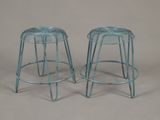 pair of blue metal stools with metal legs on a grey background