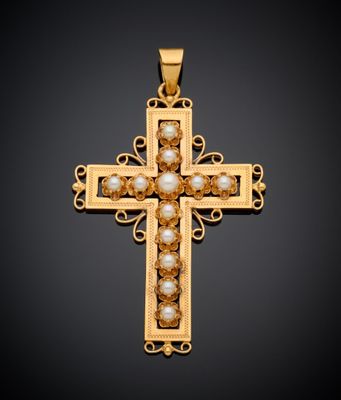 un pendentif en forme de croix en or orné de perles sur fond noir