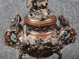 une image représentant un vase en bronze surmonté d'un oiseau