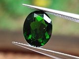 une personne tenant une pince sur laquelle est sertie une tourmaline verte