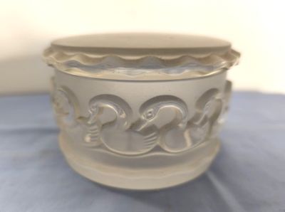 un vase blanc orné de deux oiseaux, posé sur un tissu bleu