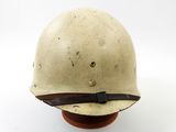 an old helmet is sitting on a wooden base on a white surface