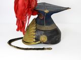 a red feather on top of a hat on a table