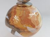 un petit vase avec un couvercle en bois posé sur une surface blanche