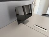 a computer monitor sitting on a desk in a cubicle